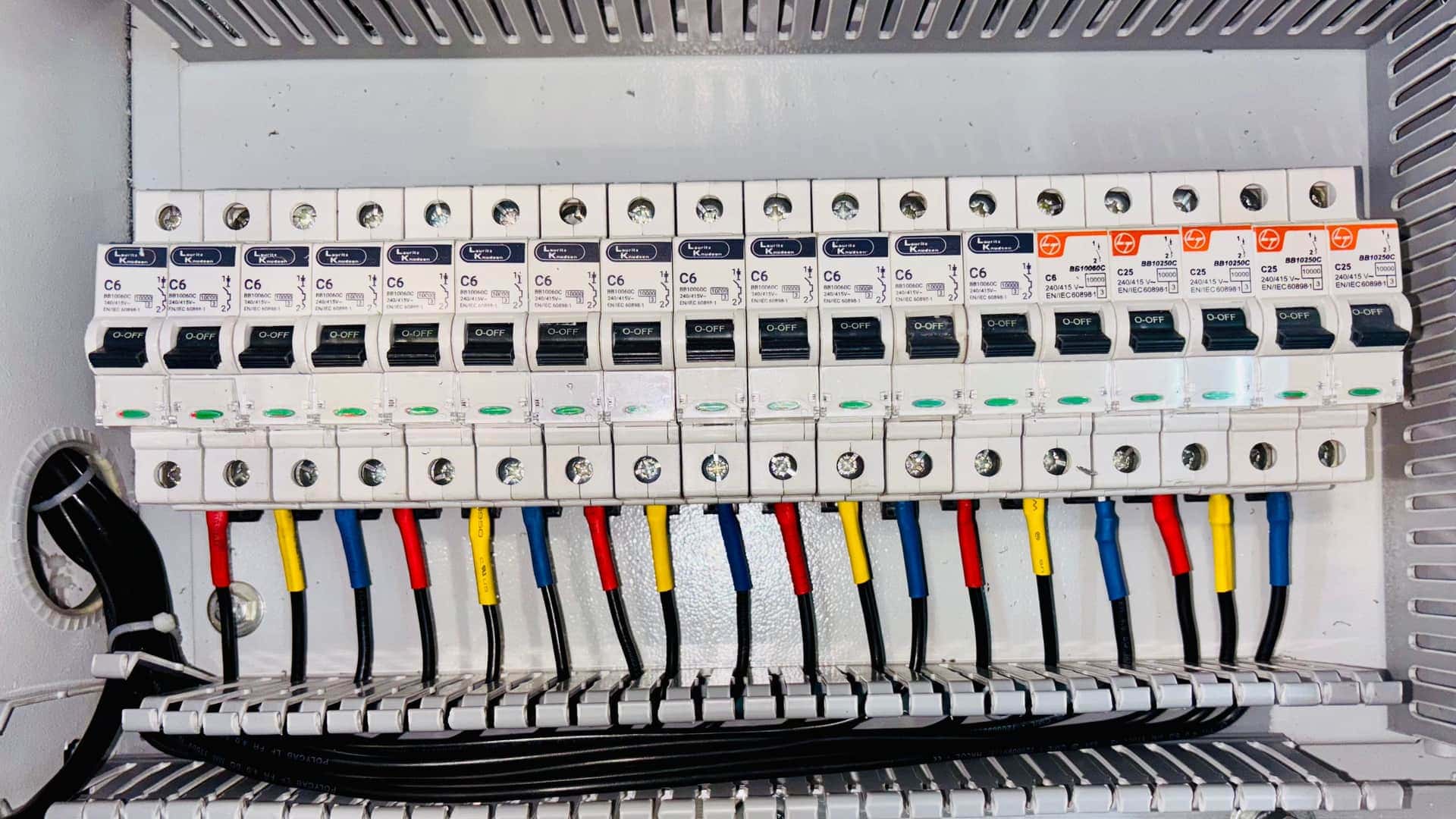 A neatly wired electrical breaker panel with color-coded conductors